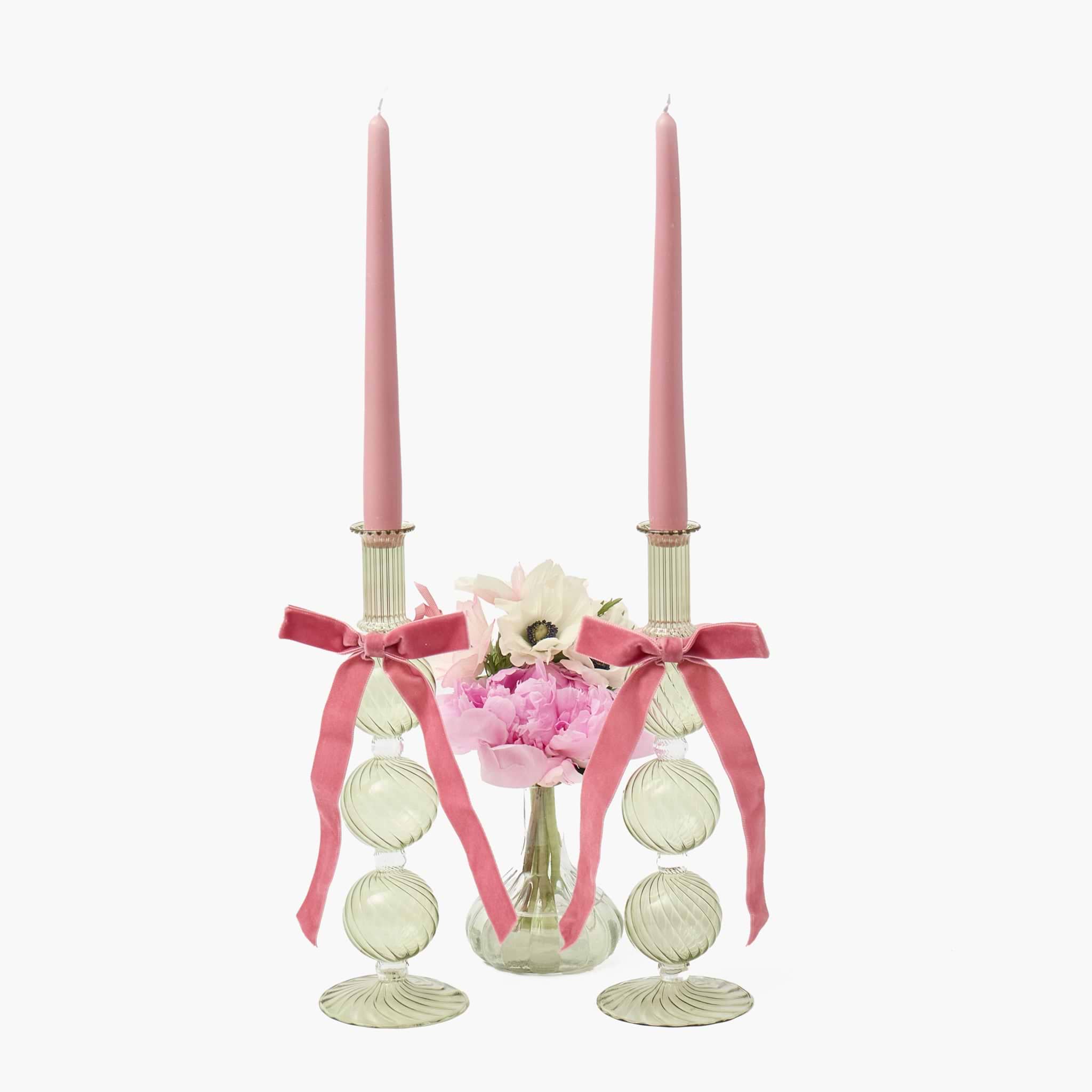 Decorative candle holder with pink candles, ribbons, and flowers on a white background