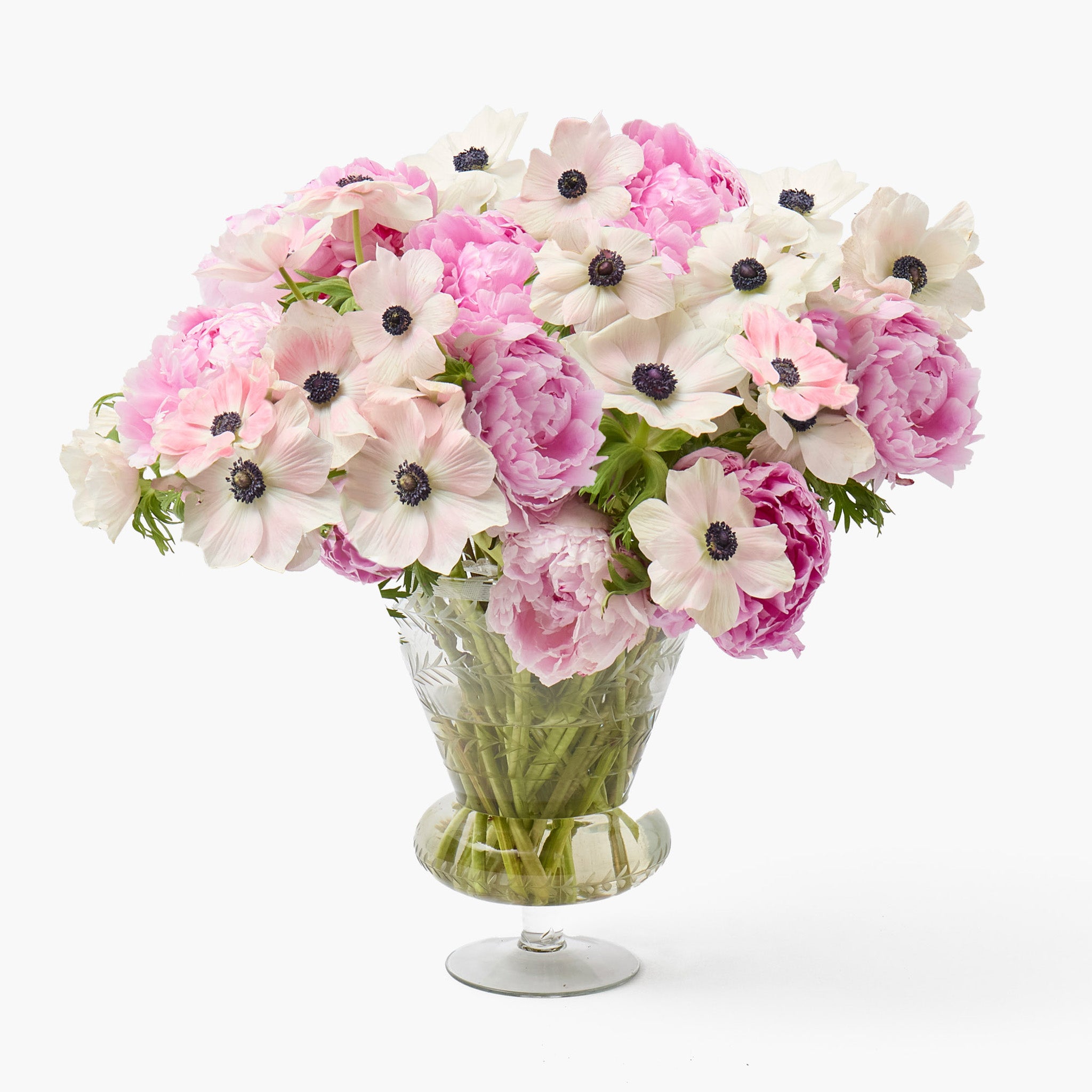 Bouquet of pink and white flowers in a clear glass vase on a white background