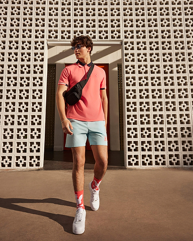 walking model wearing psycho bunny polo and short with sneakers 
