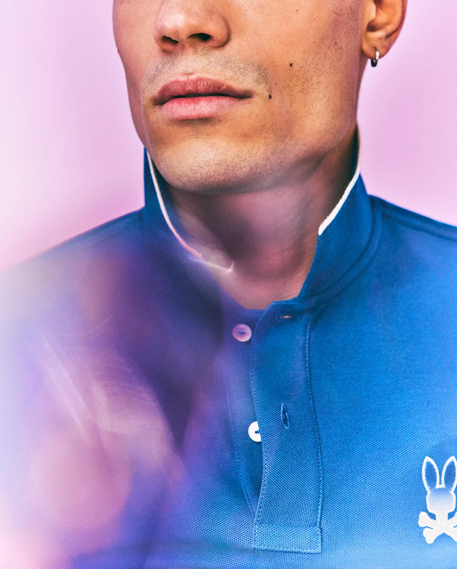 Mens Aram Pique Polo in blue, with a classic fit, pique texture, white collar trim, two-button placket with white buttons, and a small white embroidered Psycho Bunny skull logo on the left chest. (2)