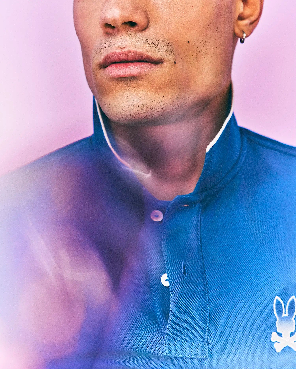 Mens Aram Pique Polo in blue, with a classic fit, pique texture, white collar trim, two-button placket with white buttons, and a small white embroidered Psycho Bunny skull logo on the left chest. (2)