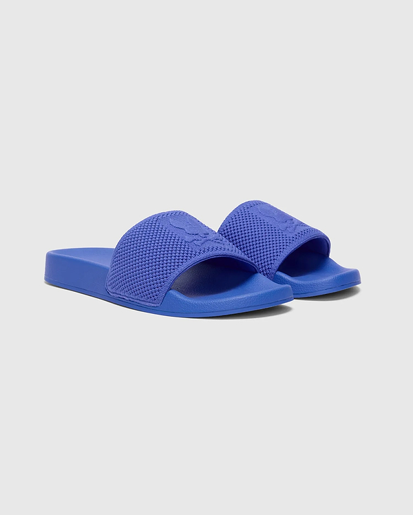 Royal Blue Kids Knit Slides featuring a textured knitted strap with an embossed Psycho Bunny skull logo, and a smooth sole.