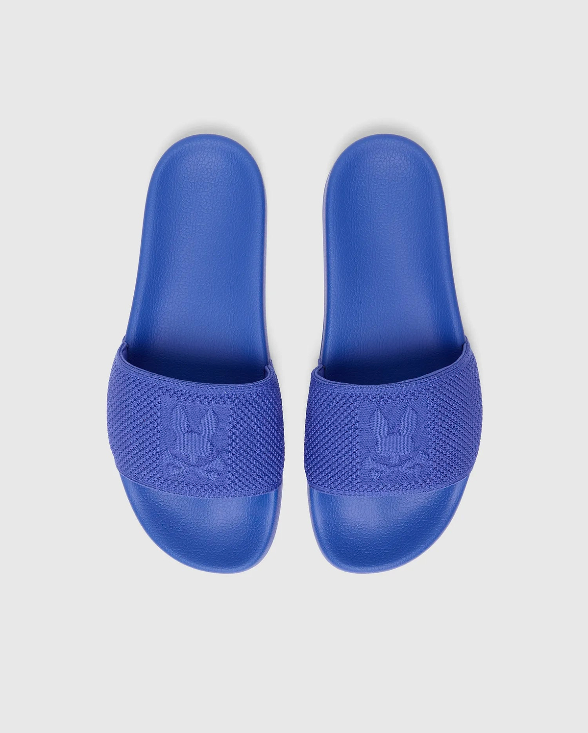 Kids Knit Slides in vibrant royal blue, featuring a comfortable textured sole and a knitted strap with a prominent woven Psycho Bunny skull logo.