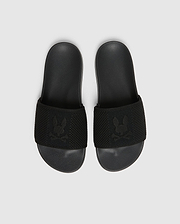 A pair of black Psycho Bunny KIDS KNIT SLIDES - B0A377F200, featuring a textured strap with an embroidered stylized rabbit head logo and a molded footbed for comfort, are placed side by side on a light gray background.