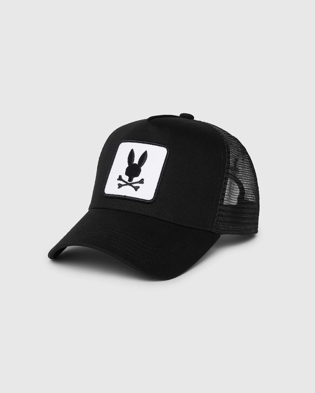 The Psycho Bunny KIDS BUNNY PATCH TRUCKER CAP (B0A965C200) features breathable mesh panels and a front patch with a white bunny logo, including a black bunny head and crossbones.