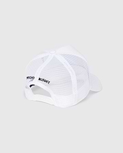 The KIDS BUNNY PATCH TRUCKER CAP - B0A965C200 by Psycho Bunny is a white mesh trucker cap with the iconic Bunny logo patch. It features "Psycho Bunny" text on the side, a white brim, snapback closure, and a top button, all set against a light gray background.