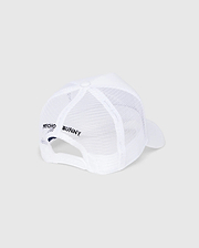 The KIDS BUNNY PATCH TRUCKER CAP - B0A965C200 by Psycho Bunny is a white mesh trucker cap with the iconic Bunny logo patch. It features "Psycho Bunny" text on the side, a white brim, snapback closure, and a top button, all set against a light gray background.