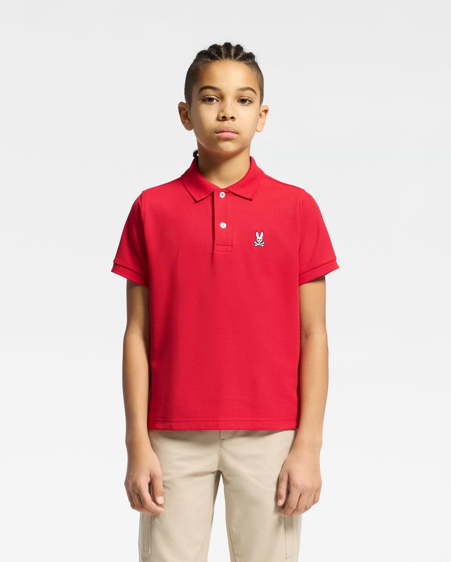 Red kids classic pique polo shirt with a classic fit, featuring a two-button placket, ribbed collar and cuffs, and a small embroidered white Psycho Bunny skull logo on the left chest.