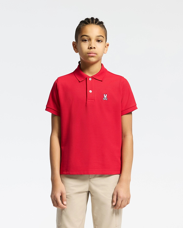 Red kids classic pique polo shirt with a classic fit, featuring a two-button placket, ribbed collar and cuffs, and a small embroidered white Psycho Bunny skull logo on the left chest.