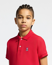 Vibrant red kids classic pique polo shirt, featuring a classic fit, two white button placket, and a small, multi-color embroidered Psycho Bunny skull logo on the left chest.