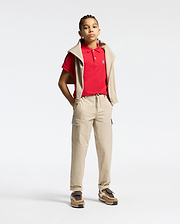 Red kids classic pique polo shirt with a classic fit, white two-button placket, and small embroidered white Psycho Bunny skull logo on the left chest, styled with beige cargo pants and a matching sweatshirt.