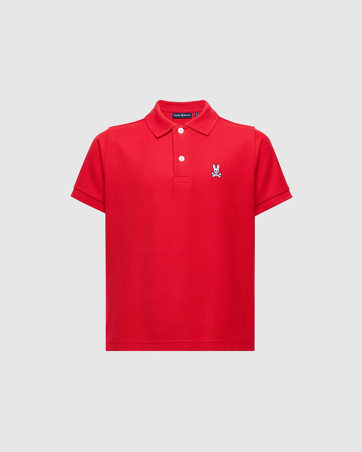 Red kids classic pique polo shirt with a two-button placket, white buttons, and a small, embroidered white, blue, and black Psycho Bunny skull logo on the left chest.