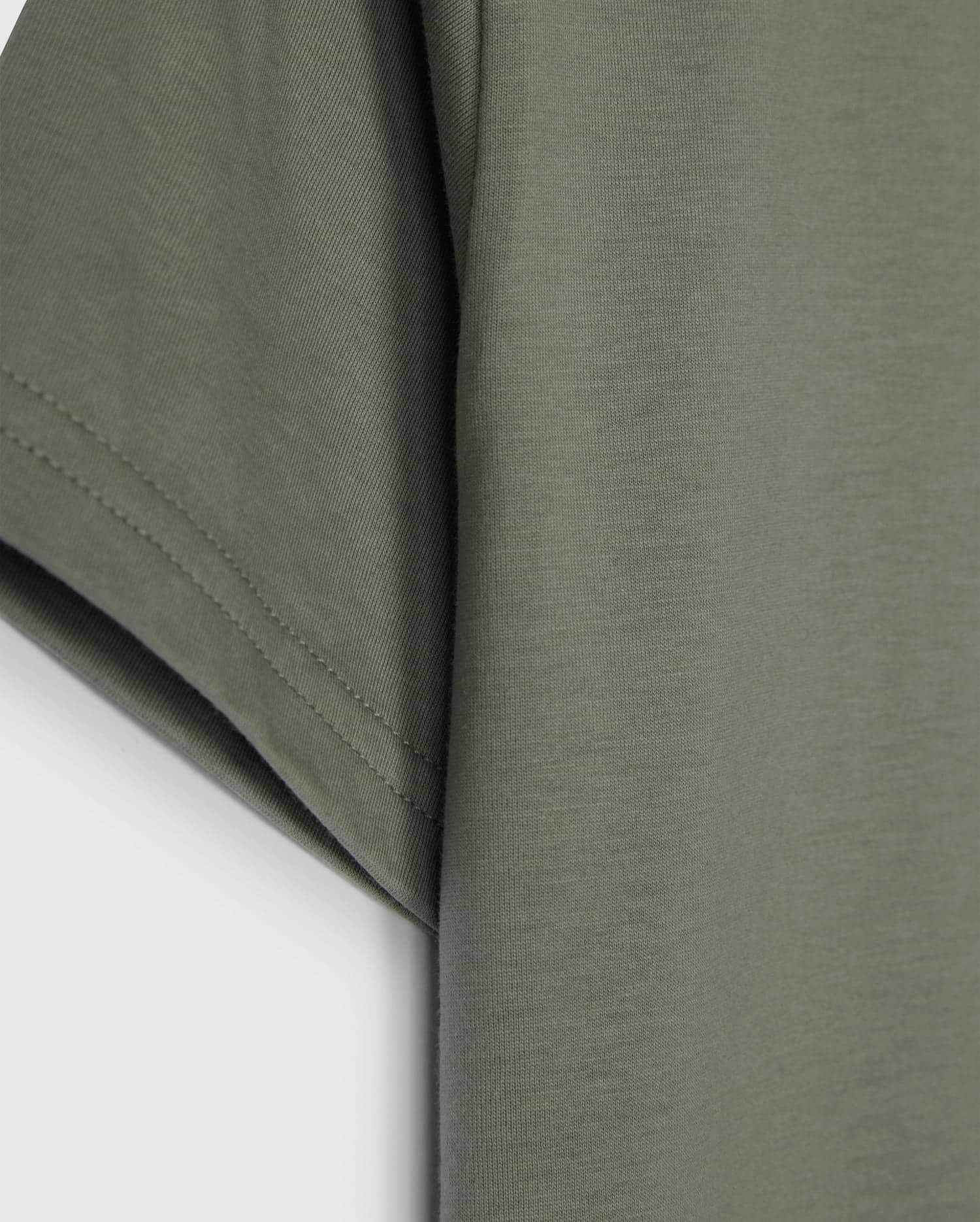 The KIDS CLASSIC CREW NECK TEE - B0U014B200 by Psycho Bunny, in olive green, showcases sleeve and side details on a plain white background. Made from 100% Pima cotton, its texture and stitching make it an ideal back-to-school choice.