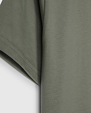 The KIDS CLASSIC CREW NECK TEE - B0U014B200 by Psycho Bunny, in olive green, showcases sleeve and side details on a plain white background. Made from 100% Pima cotton, its texture and stitching make it an ideal back-to-school choice.