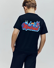 A child faces away wearing the Psycho Bunny KIDS MONTREAL TEE (B0U381F200), a black 100% Pima cotton T-shirt with colorful Montreal landmarks and "Montreal" on the back, paired with black shorts.
