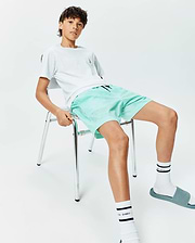 Kids Samos Hydrochromic Printed Swim Trunk in mint green with a subtle all-over Psycho Bunny skull pattern, paired with a white jersey t-shirt featuring a small chest logo. (4)