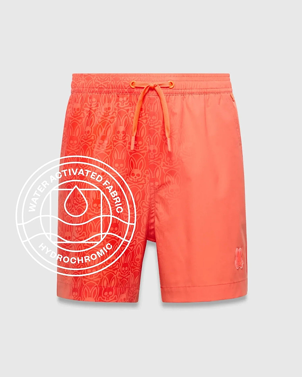 Kids Samos Hydrochromic Printed Swim Trunk in vibrant coral, featuring a water-activated all-over Psycho Bunny skull pattern on the left leg and a small embroidered logo on the right hem.