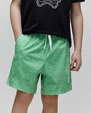 Kids Samos Hydrochromic Printed Swim Trunk, vibrant green with a subtle tonal all-over Psycho Bunny skull and crossbones pattern, white drawstring, and small embroidered white logo on the left hem.