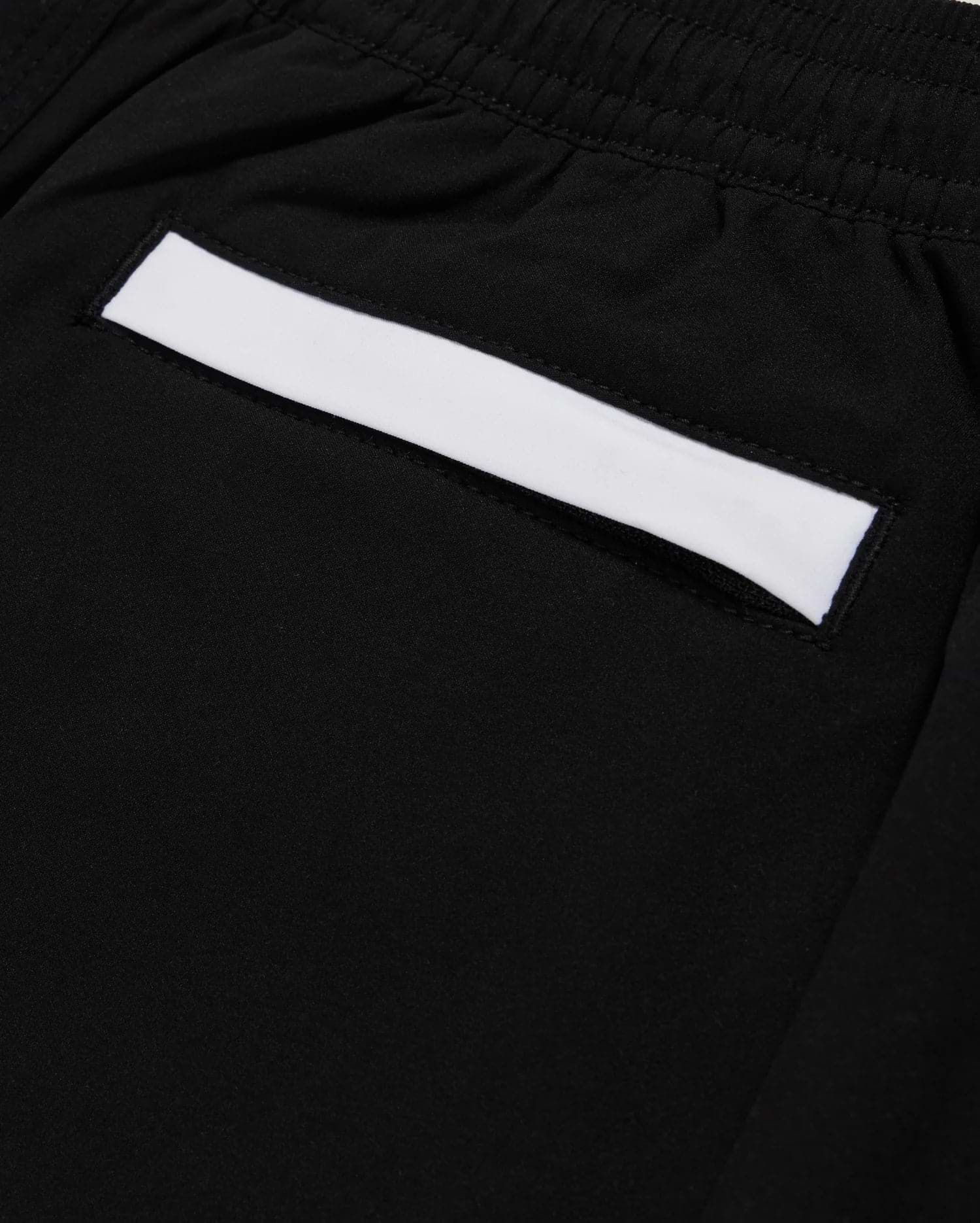 Close-up of a black fabric pocket on Psycho Bunny's KIDS PARKER HYDROCHROMIC SWIM TRUNK - B0W646C200, featuring an elastic waistband. The pocket highlights a white rectangular strip across its top edge and is made from quick-dry material.