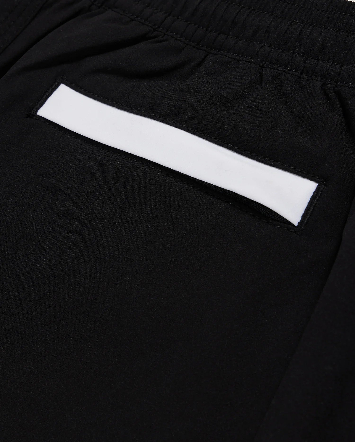 Close-up of a black fabric pocket on Psycho Bunny's KIDS PARKER HYDROCHROMIC SWIM TRUNK - B0W646C200, featuring an elastic waistband. The pocket highlights a white rectangular strip across its top edge and is made from quick-dry material.