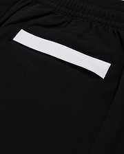 Close-up of a black fabric pocket on Psycho Bunny's KIDS PARKER HYDROCHROMIC SWIM TRUNK - B0W646C200, featuring an elastic waistband. The pocket highlights a white rectangular strip across its top edge and is made from quick-dry material.