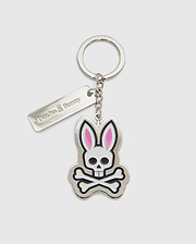 Introducing the CLASSIC BUNNY KEYCHAIN - B6A372E200 from Psycho Bunny, a fashionable metal accessory showcasing a cartoon bunny skull and crossbones design with distinctive pink ears. This practical everyday keychain features a sleek rectangular tag engraved with "Psycho Bunny." Complemented by a silver-colored chain and keyring, it adds a chic touch to your essentials.
