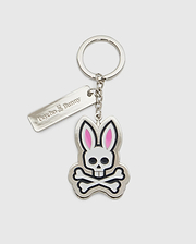 Introducing the CLASSIC BUNNY KEYCHAIN - B6A372E200 from Psycho Bunny, a fashionable metal accessory showcasing a cartoon bunny skull and crossbones design with distinctive pink ears. This practical everyday keychain features a sleek rectangular tag engraved with "Psycho Bunny." Complemented by a silver-colored chain and keyring, it adds a chic touch to your essentials.
