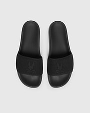 The Psycho Bunny MENS KNIT SLIDES - B6A474F200 are black slide sandals with textured straps and feature a flocked Bunny emblem design. They offer comfort with a molded footbed and are displayed on a plain light grey background.