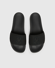 The Psycho Bunny MENS KNIT SLIDES - B6A474F200 are black slide sandals with textured straps and feature a flocked Bunny emblem design. They offer comfort with a molded footbed and are displayed on a plain light grey background.