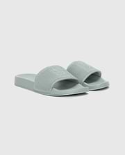 The Psycho Bunny MENS KNIT SLIDES - B6A474F200 are light green textured pool slides with open toes, a wide strap, and an ergonomically molded footbed, shown on a plain white background.