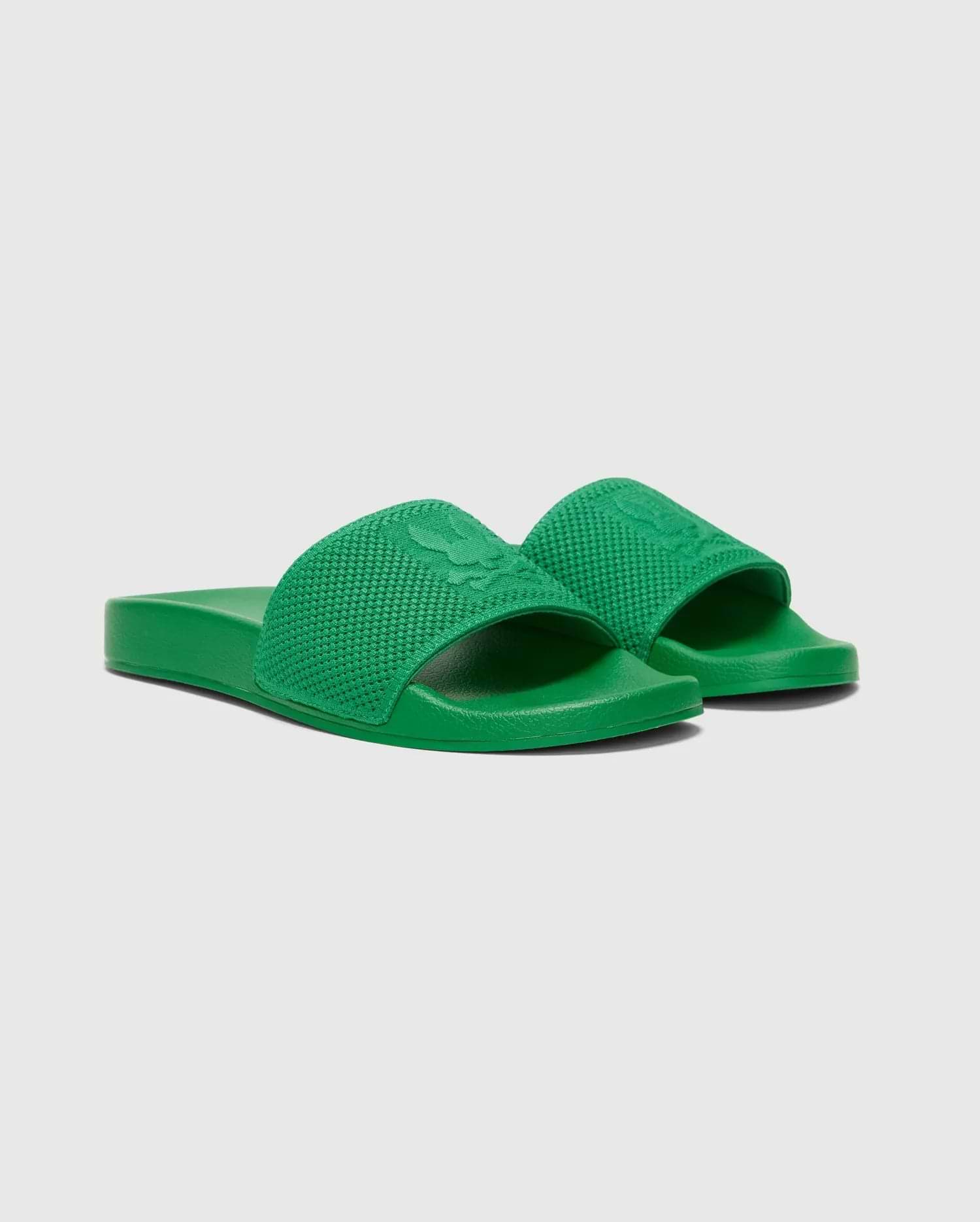 Vibrant Kelly green Mens Knit Slides, a premium streetwear design, featuring a prominent textured knit strap with a large embossed Psycho Bunny skull logo, and a comfortable, smooth monochromatic sole.