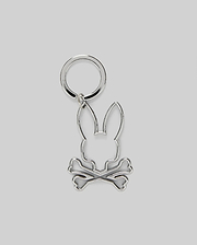 The Psycho Bunny MENS OUTLINE BUNNY KEYCHAIN (B6A565E200) is a durable silver accessory featuring a rabbit head over crossed bones, crafted from zinc alloy and set on a plain gray background.