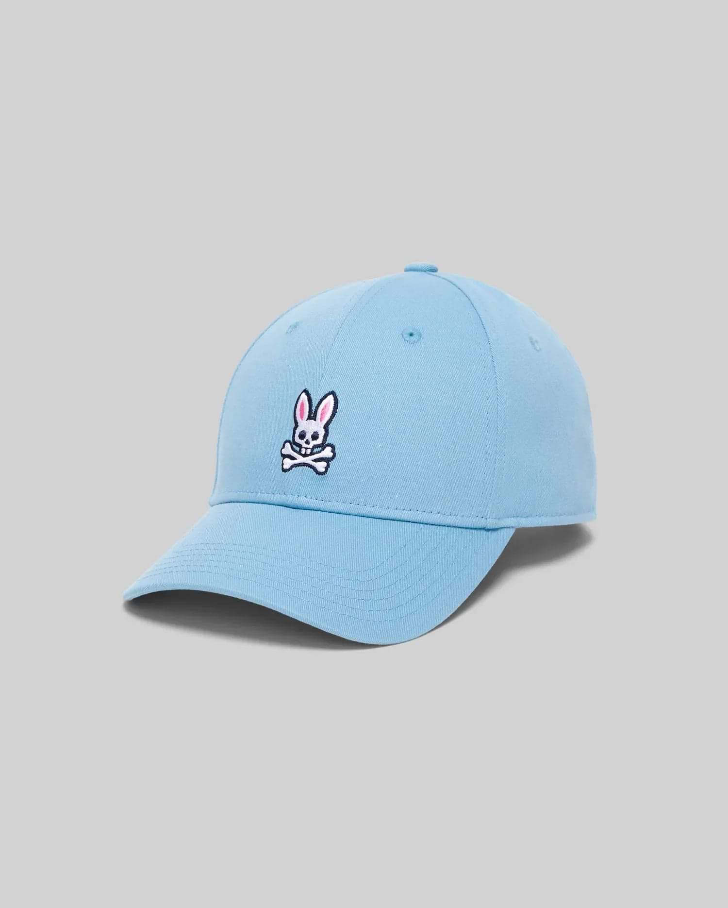 Mens Classic Baseball Cap in sky blue cotton twill, featuring a classic fit and a medium-sized embroidered Psycho Bunny skull logo in white, black, and pink on the front.