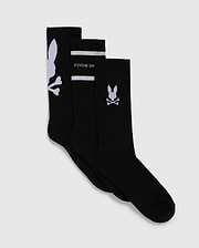Displayed are three pairs of black sport socks from Psycho Bunny, known as the MENS 3 PACK SPORT SOCK - B6F997D200. Crafted from luxurious Peruvian pima cotton, each pair showcases a unique white design: one with a large bunny skull motif near the top, another featuring "PSYCHO BUNNY" text and horizontal stripes, and the last with a small bunny skull and crossbones near the top.