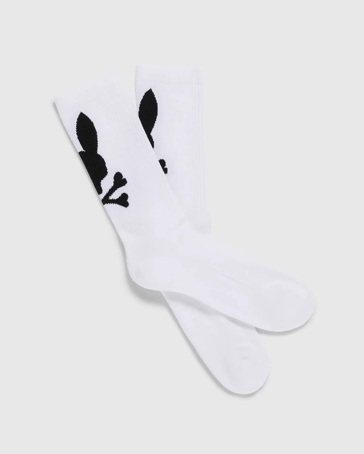A pack of 3 Men's Sport Socks (B6F997D200) by Psycho Bunny, crafted from luxurious Peruvian Pima cotton in white, features a distinctive black graphic design of a skull with bunny ears and bones. The socks are displayed with one pair slightly overlapping the other on a plain, light-colored background.