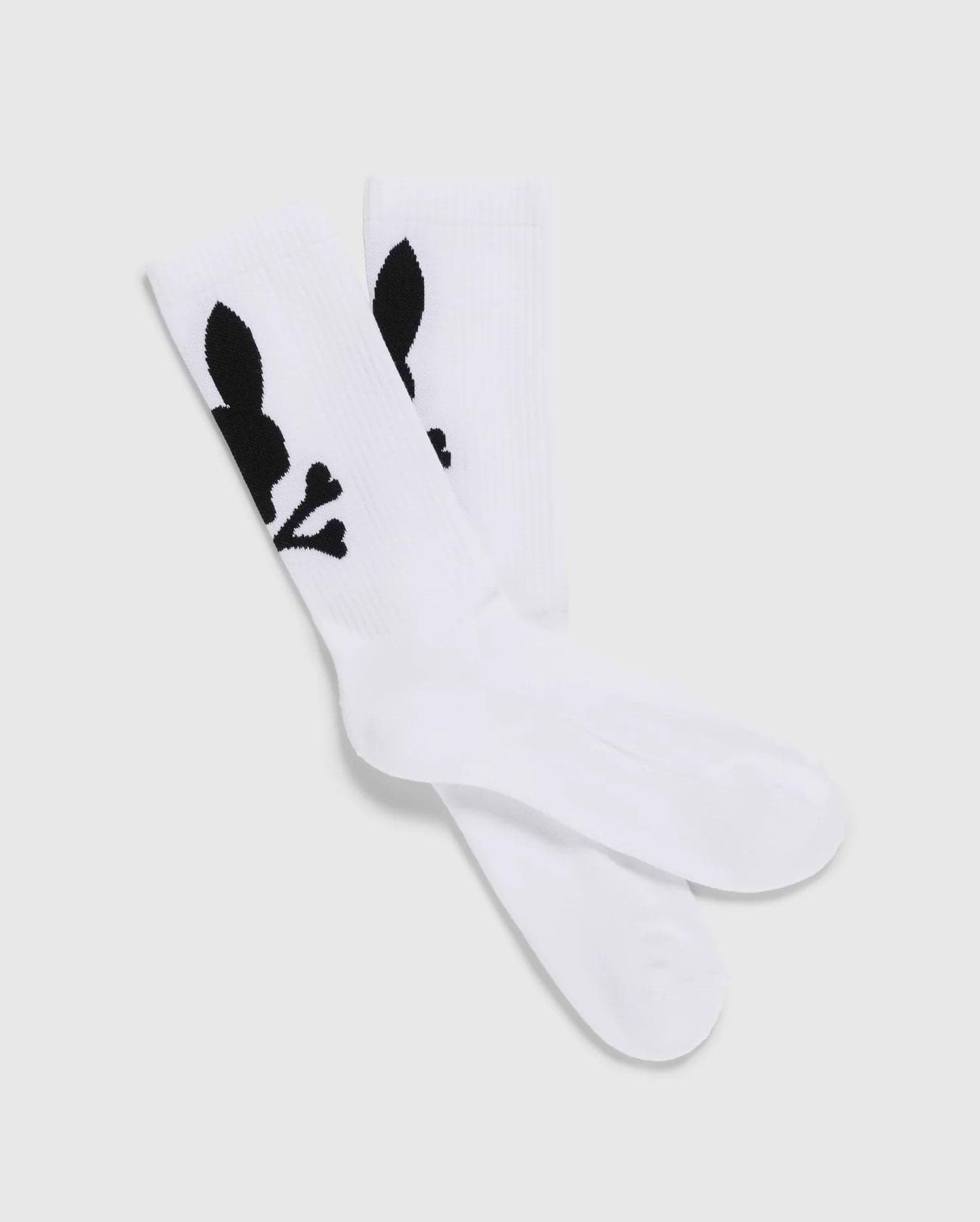 A pack of 3 Men's Sport Socks (B6F997D200) by Psycho Bunny, crafted from luxurious Peruvian Pima cotton in white, features a distinctive black graphic design of a skull with bunny ears and bones. The socks are displayed with one pair slightly overlapping the other on a plain, light-colored background.