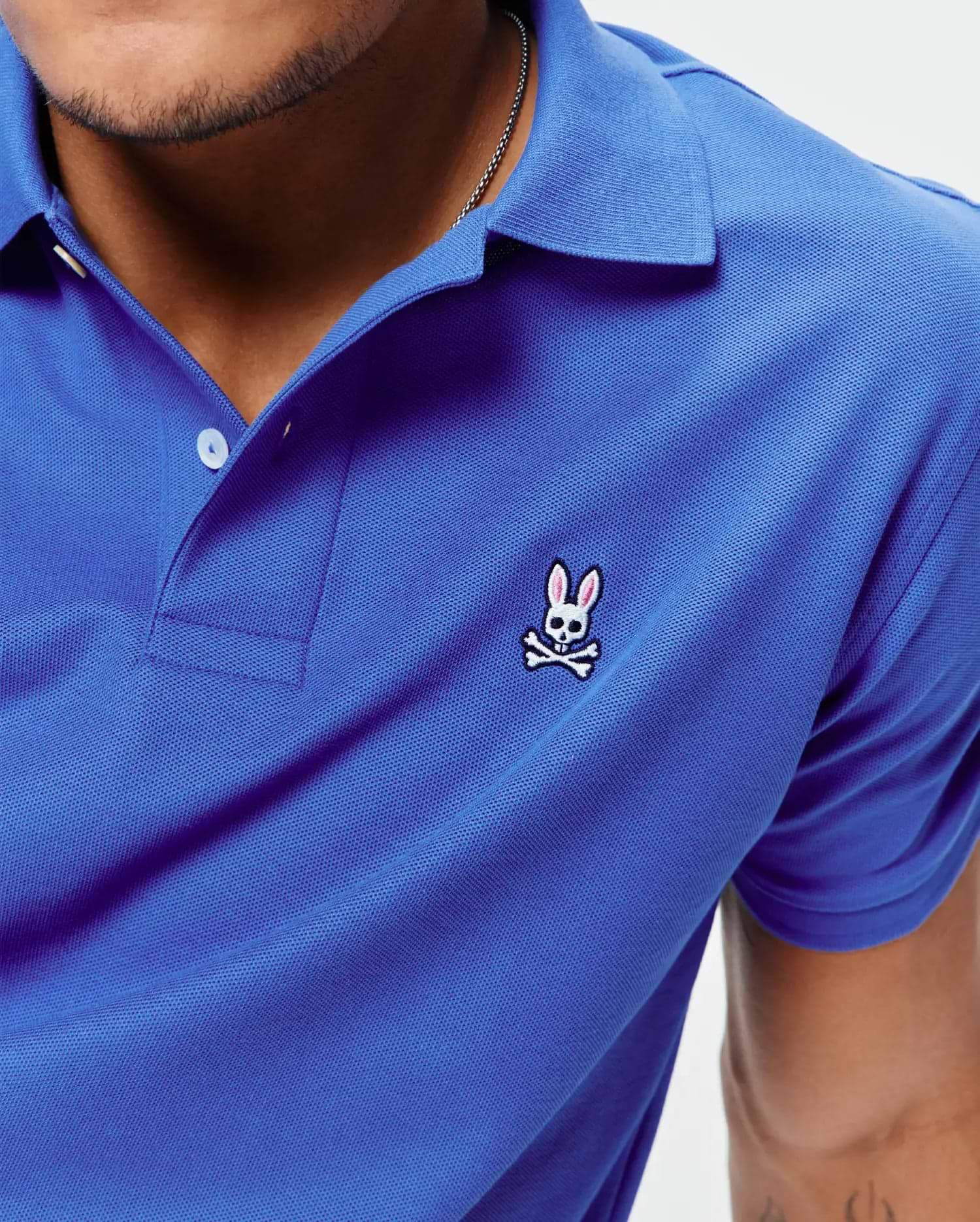 Royal blue Mens Classic Pique Polo with a classic fit, featuring a textured pique knit, white two-button placket, and a small embroidered pink and white Psycho Bunny skull logo on the left chest.