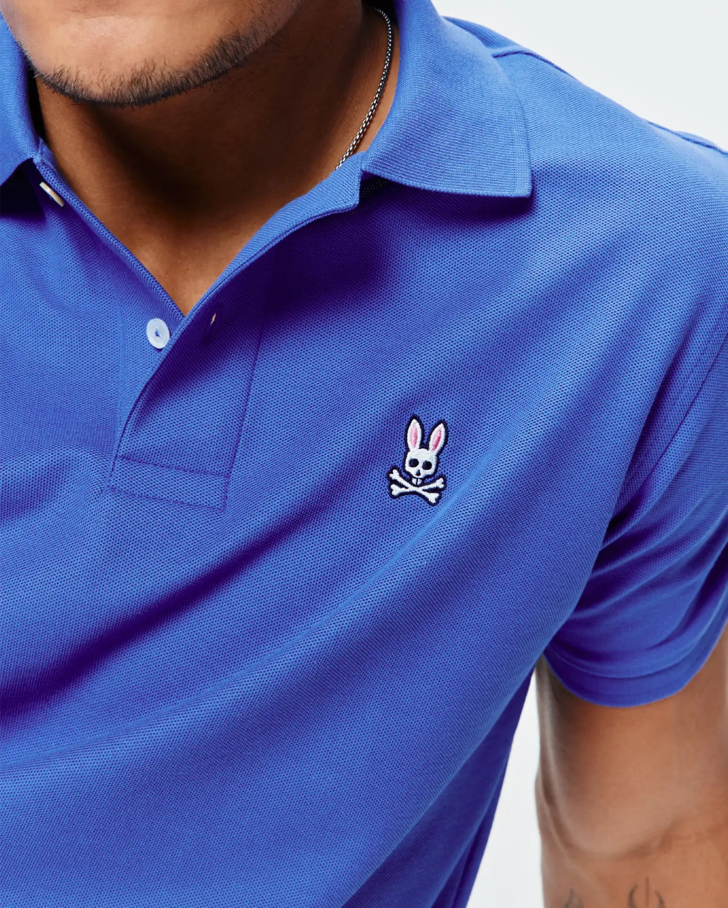 Royal blue Mens Classic Pique Polo with a classic fit, featuring a textured pique knit, white two-button placket, and a small embroidered pink and white Psycho Bunny skull logo on the left chest.
