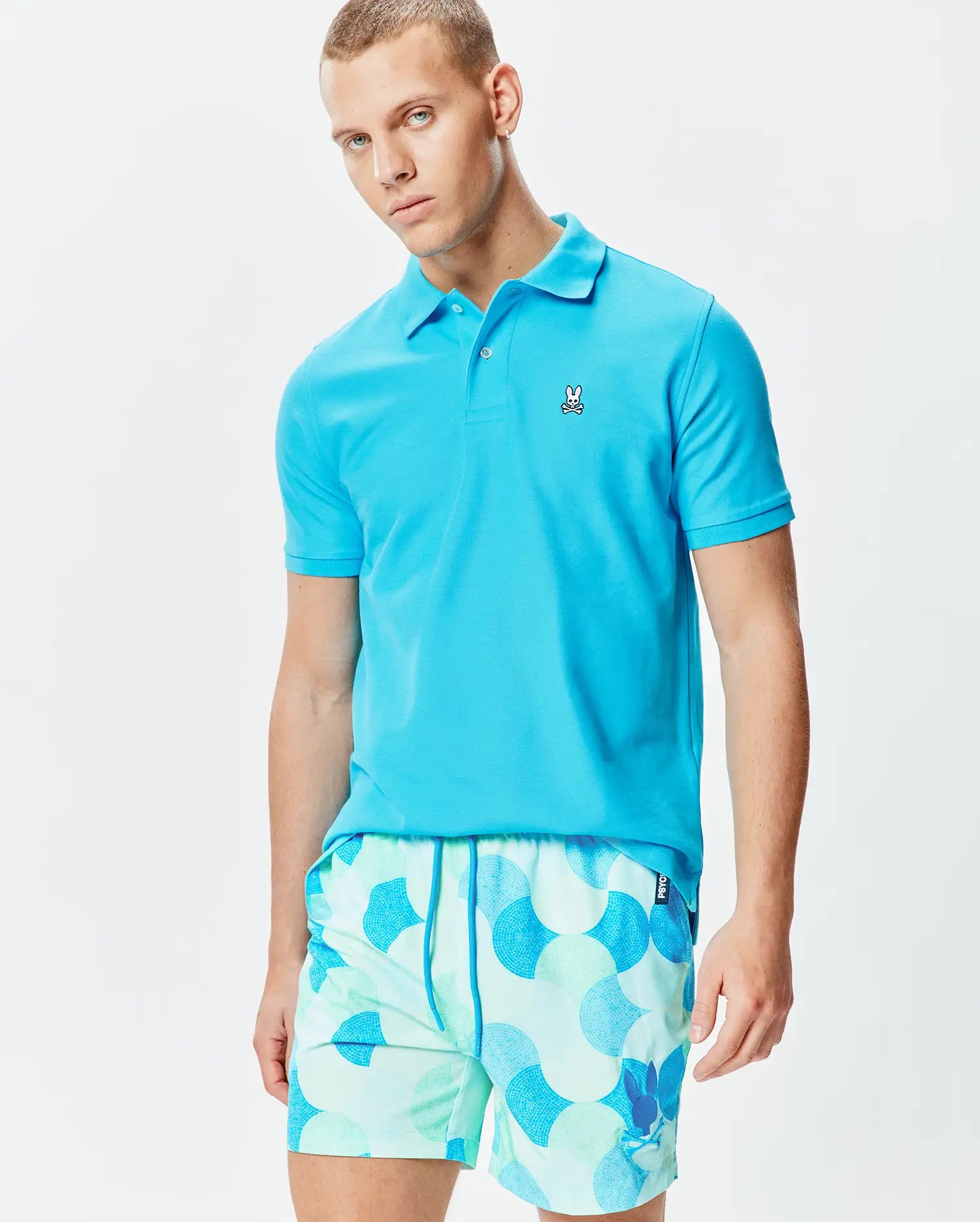 Mens Classic Pique Polo in vibrant turquoise blue, featuring a classic fit and textured pique fabric, with a small embroidered white Psycho Bunny skull logo on the left chest. (3)