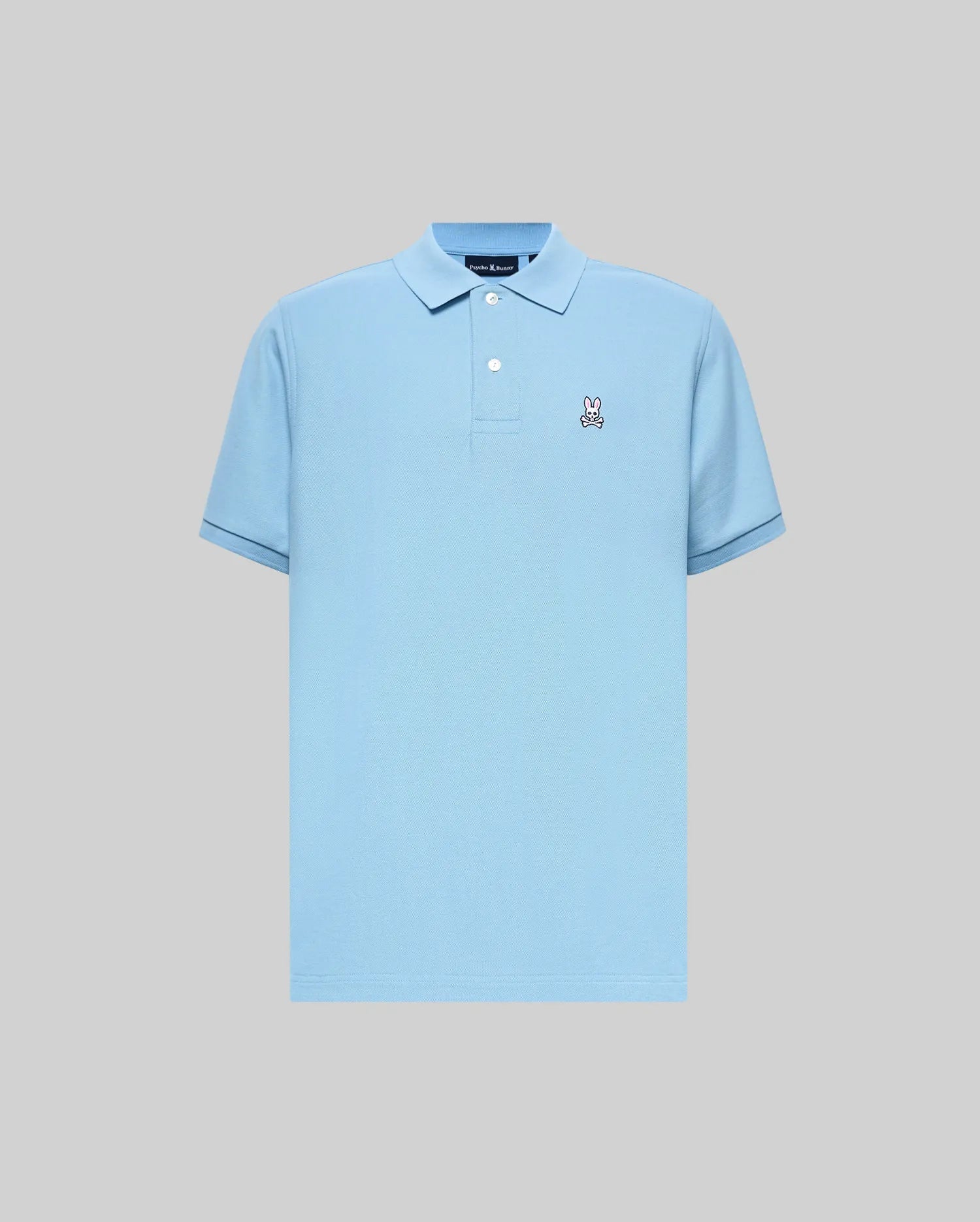 Mens Classic Pique Polo in light blue, classic fit, pique knit fabric. Features a small embroidered Psycho Bunny skull logo on the left chest, two white buttons, and dark blue tipping on ribbed cuffs.