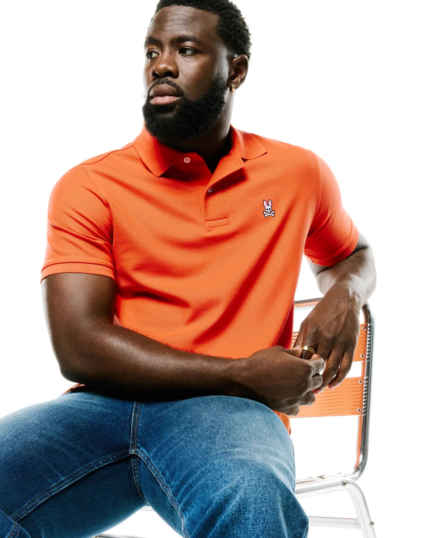 Men's Classic Pima Pique Polo in vibrant orange, featuring a classic fit, textured pique fabric, white two-button placket, and a small embroidered Psycho Bunny skull logo on the left chest. (3)
