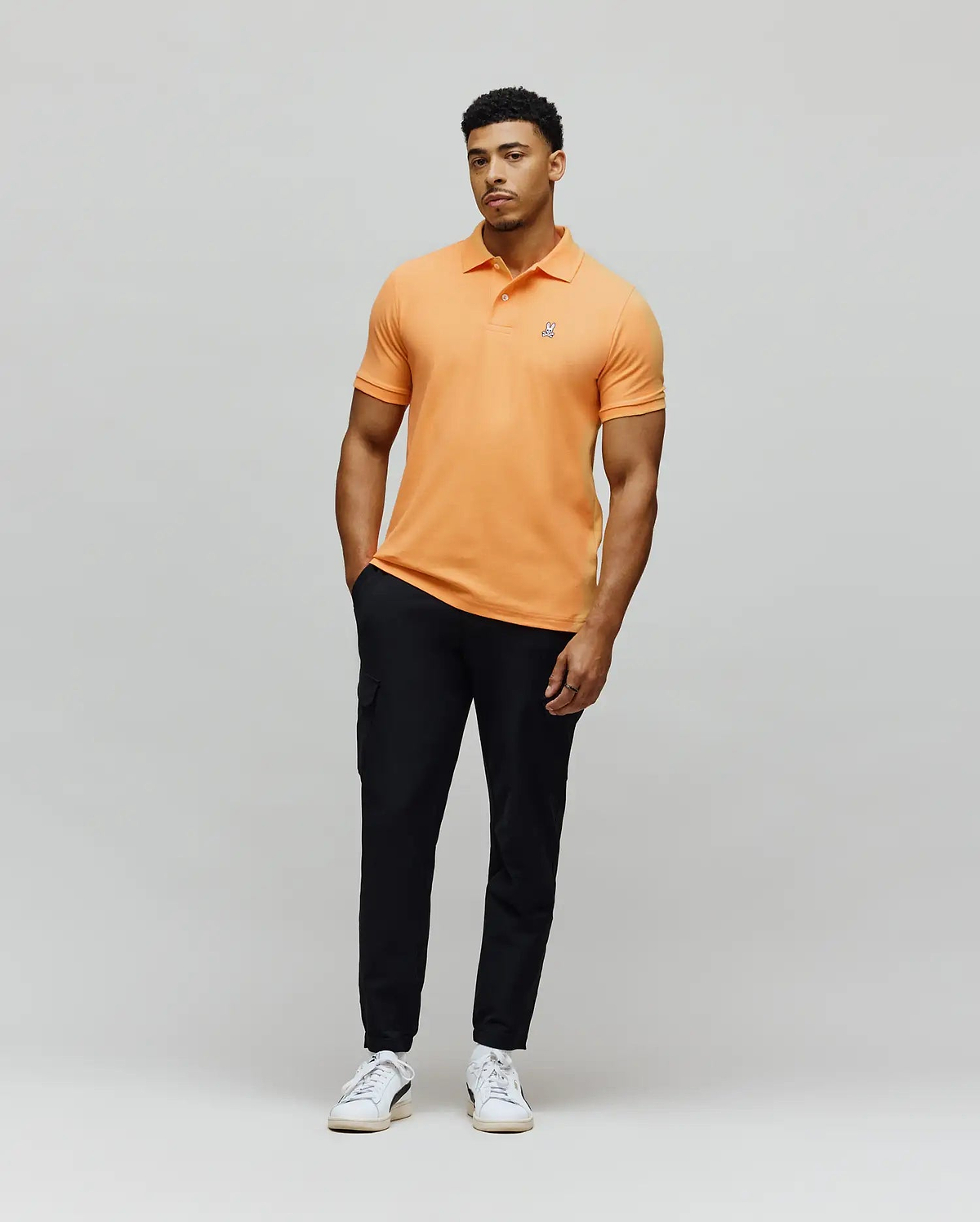 Mens Classic Pique Polo in vibrant orange, featuring a classic fit, pique knit texture, and a small embroidered Psycho Bunny skull logo on the left chest. (2)