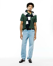 Mens Classic Pique Polo in dark green, featuring a classic fit, pique texture, and a small embroidered Psycho Bunny skull logo on the left chest, styled with a navy and white striped sweater.
