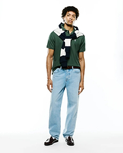 Mens Classic Pique Polo in dark green, featuring a classic fit, pique texture, and a small embroidered Psycho Bunny skull logo on the left chest, styled with a navy and white striped sweater.
