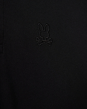 Close-up of the Psycho Bunny MENS JAMES PREMIUM PIQUE POLO SHIRT - B6K945D200 in black, showcasing an embroidered logo depicting a rabbit's head with crossbones underneath. The all-black logo blends subtly with the fabric, adding a refined touch. Made from premium Pima cotton, this durable shirt offers both style and comfort.