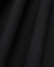 Close-up of the black Pima cotton fabric under soft lighting, showcasing the fine weave and subtle folds of Psycho Bunny's MENS JAMES PREMIUM PIQUE POLO SHIRT - B6K945D200. The surface appears smooth and uniform, with shadows emphasizing the gentle undulations typical of this high-quality polo shirt.