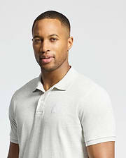 A man in a slim fit Psycho Bunny MENS JAMES PIQUE POLO - B6K945D200, light gray and made from durable Pima cotton, stands against a plain background. The shirt has a small embroidered logo on the left chest. He has short hair and gazes at the camera with a neutral expression.