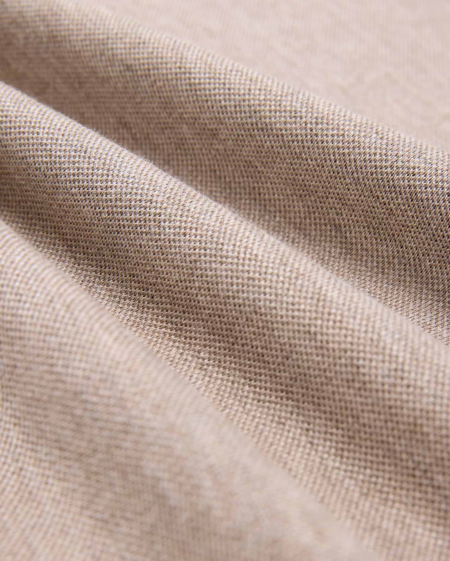 Close-up of beige Pima cotton fabric showcasing its fine weave and texture. The material is slightly draped, forming gentle folds that highlight its softness and quality, making it look ideal for crafting a durable Psycho Bunny MENS JAMES PREMIUM PIQUE POLO SHIRT - B6K945D200.