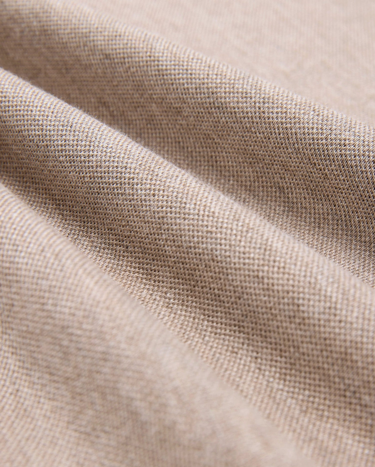 Close-up of beige Pima cotton fabric showcasing its fine weave and texture. The material is slightly draped, forming gentle folds that highlight its softness and quality, making it look ideal for crafting a durable Psycho Bunny MENS JAMES PREMIUM PIQUE POLO SHIRT - B6K945D200.