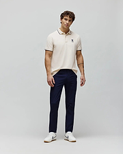Cream pique polo shirt with navy tipping on collar and cuffs, featuring a small embroidered navy Psycho Bunny skull logo on the left chest, styled with navy slim-fit Mens Maverick 10k Step Pant. (4)